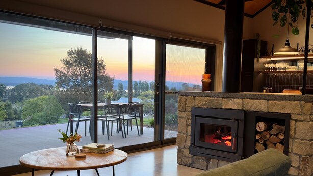A modern living room with a stone fireplace, a round coffee table, and a green sofa.