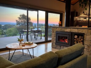Una sala de estar moderna con chimenea de piedra, una mesa de centro redonda y un sofá verde.