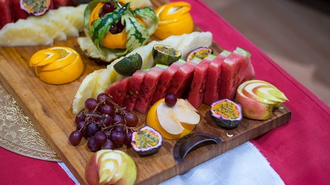 A wooden board with various fruits and a knife.