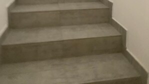A staircase leading to a room with a wooden door and a blue curtain.