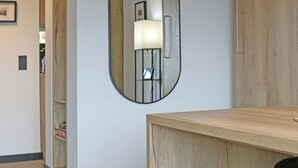 Una habitación moderna con un escritorio de madera, un espejo y una lámpara.