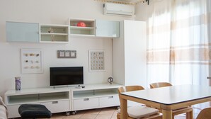 Un espace de vie compact comprenant un coin repas, un téléviseur et une kitchenette.