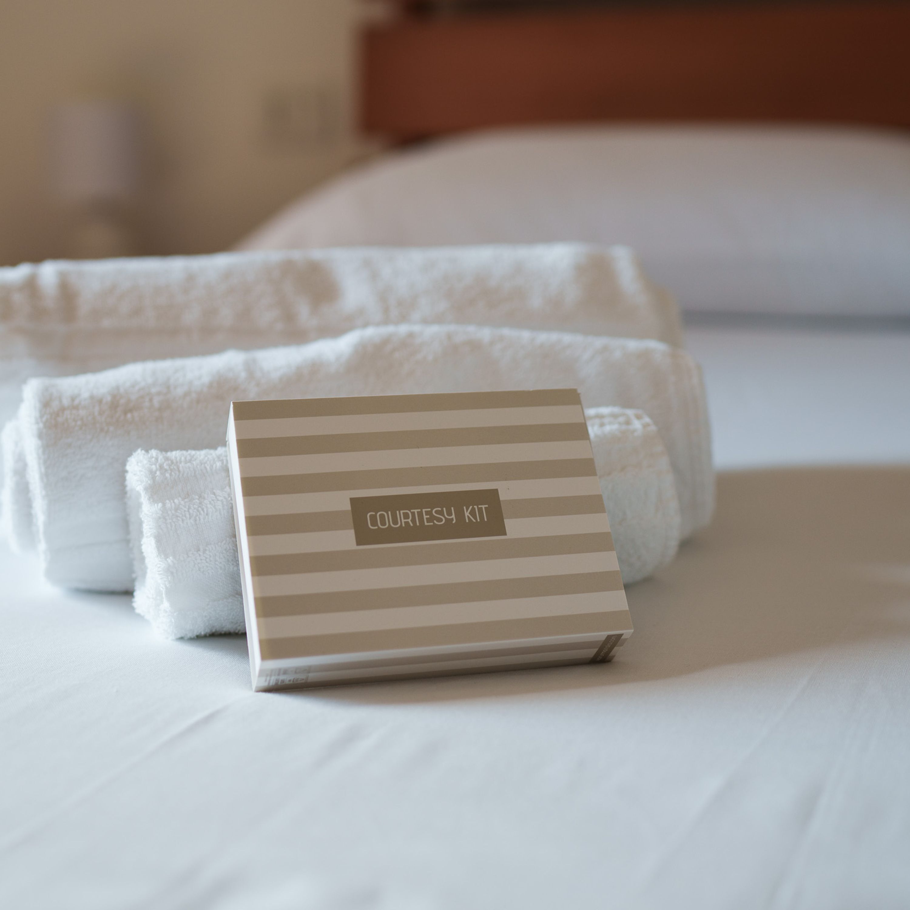 A neatly folded white towel and a labeled box on a bed.