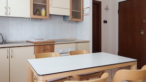 Une cuisine de taille réduite comprenant une table et des chaises, des meubles en bois et un pare-feu en carreaux.