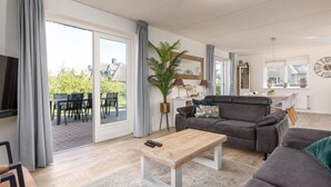 Un salon moderne avec un canapé gris, une table basse en bois et une grande plante en pot.