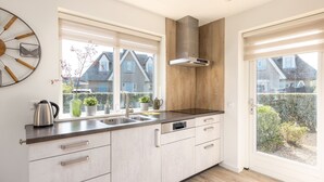 Une cuisine moderne dotée d’une grande fenêtre, d’une cuisinière encastrée et d’un lave-vaisselle.