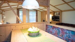 A wooden interior with a dining table, a basket of bread, and a colorful bench. - Haus Katharina by we rent (Kaprun)