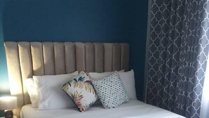 A neatly made bed with a beige headboard, white bedding, and two decorative pillows.