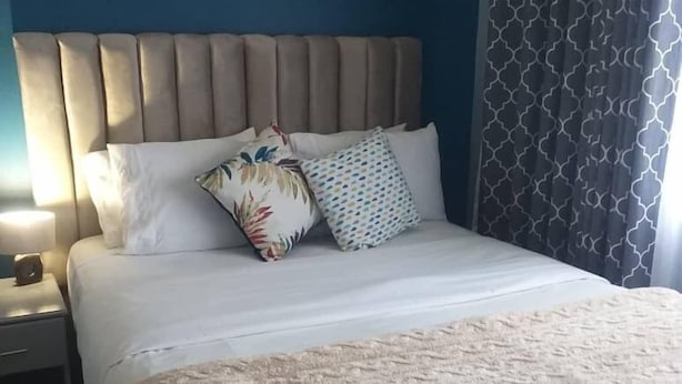A neatly made bed with a beige headboard, white bedding, and two decorative pillows.