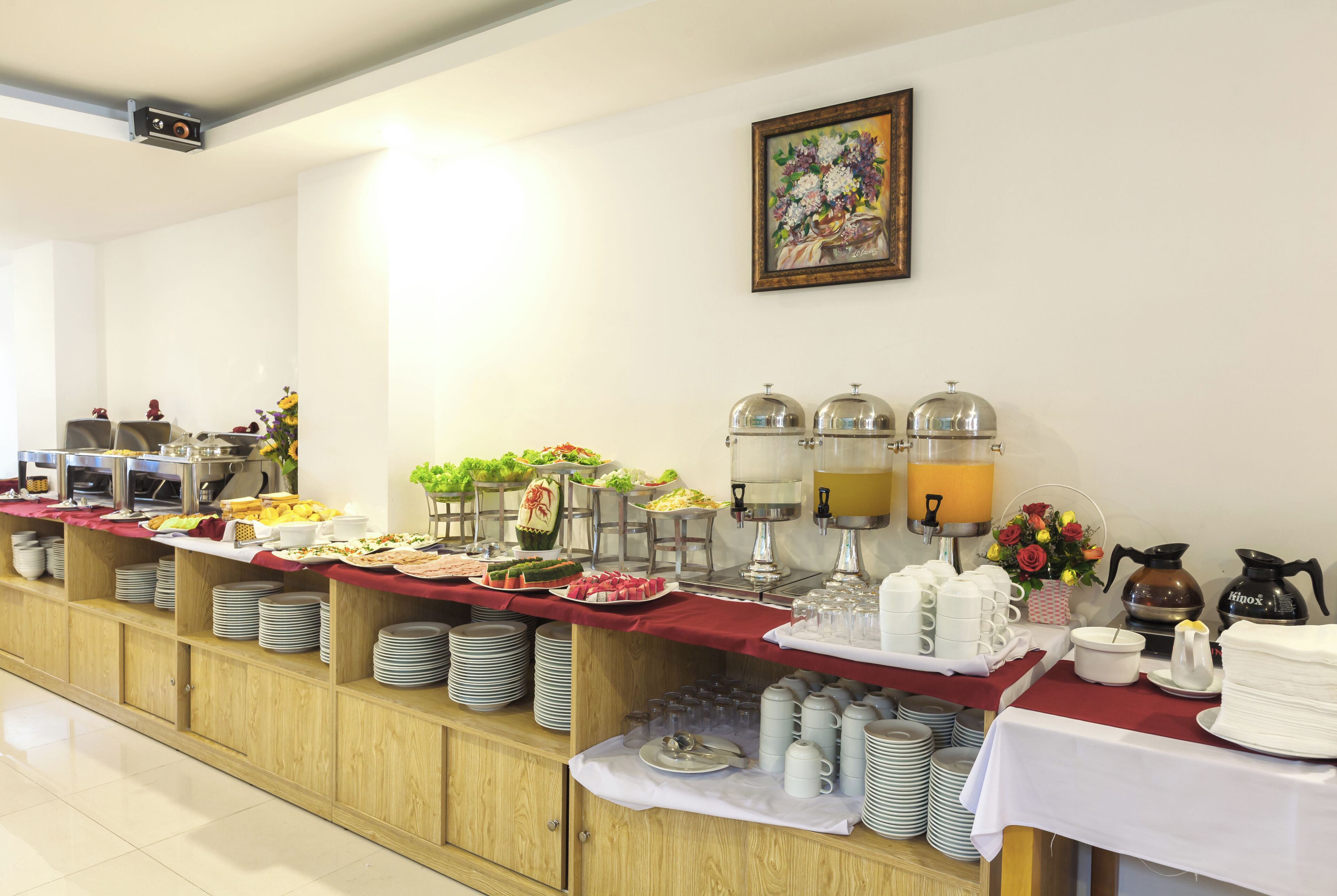 A buffet setup with various food items and beverages, including fruits, salads, and hot drinks.