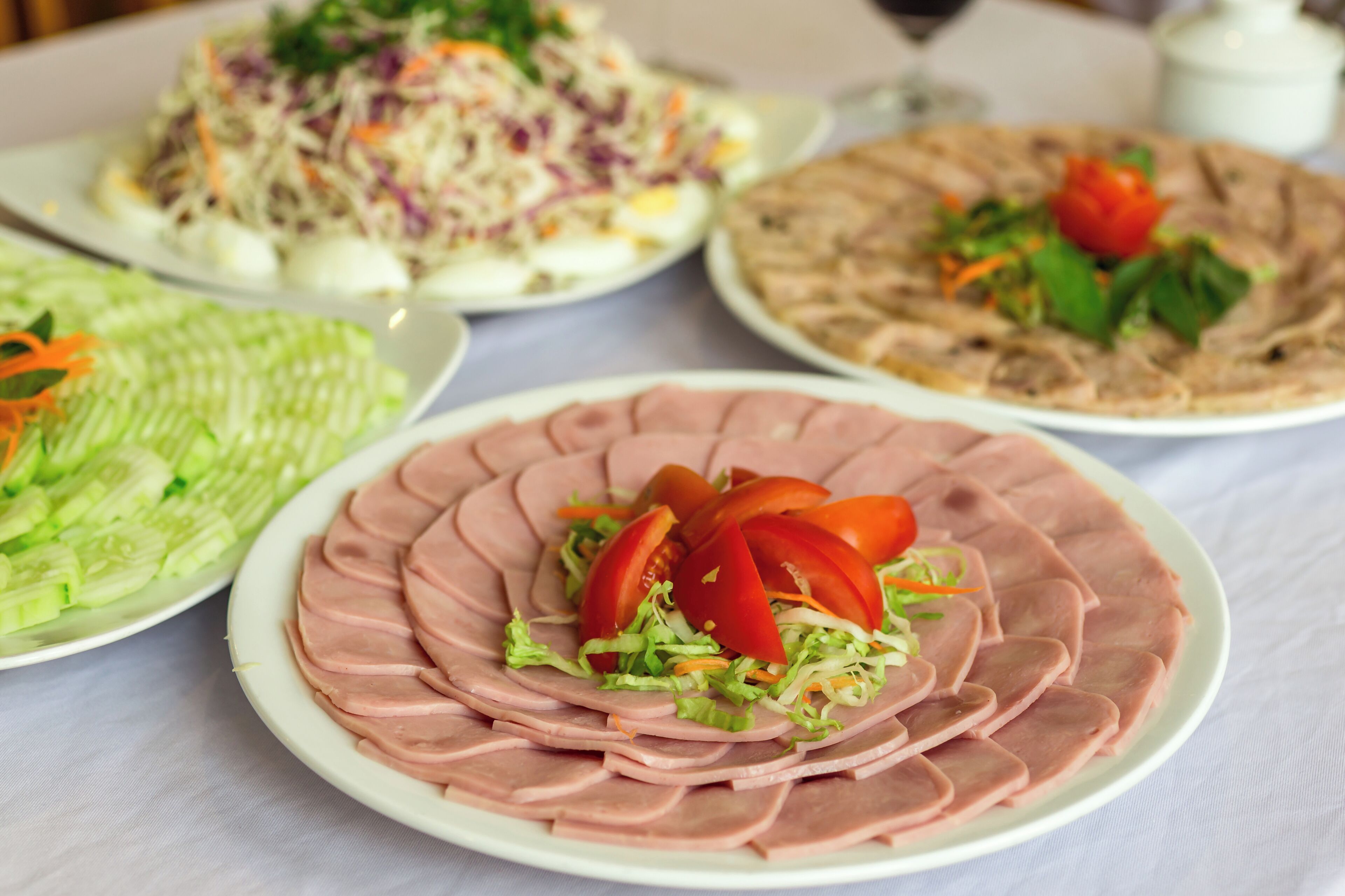 A table with various dishes including sliced meat, a salad, and a flatbread.