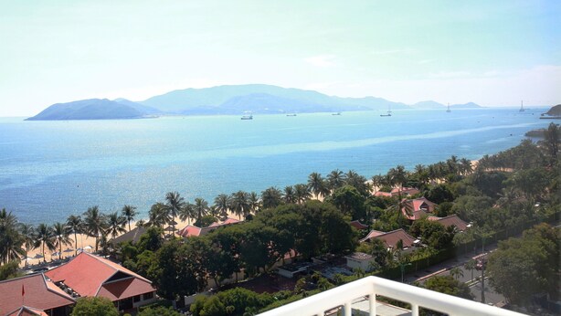 A coastal view with a beach, palm trees, and boats. - Siren Flower Hotel (Nha Trang)