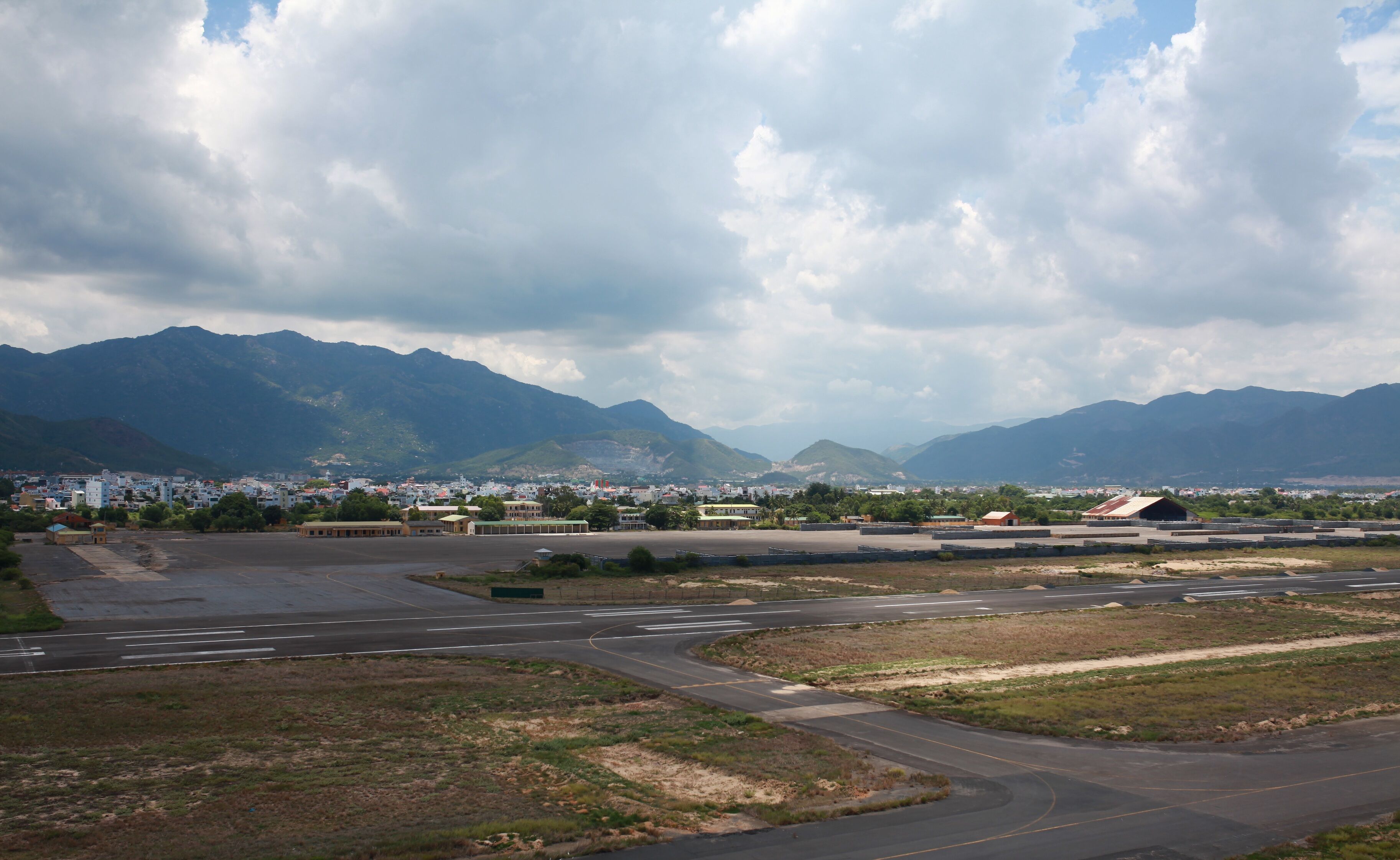 A large open area with a runway, buildings, and mountains in the background.