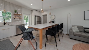 Een moderne keuken met witte kasten, een roestvrijstalen koelkast en een eethoek met een tafel en stoelen.