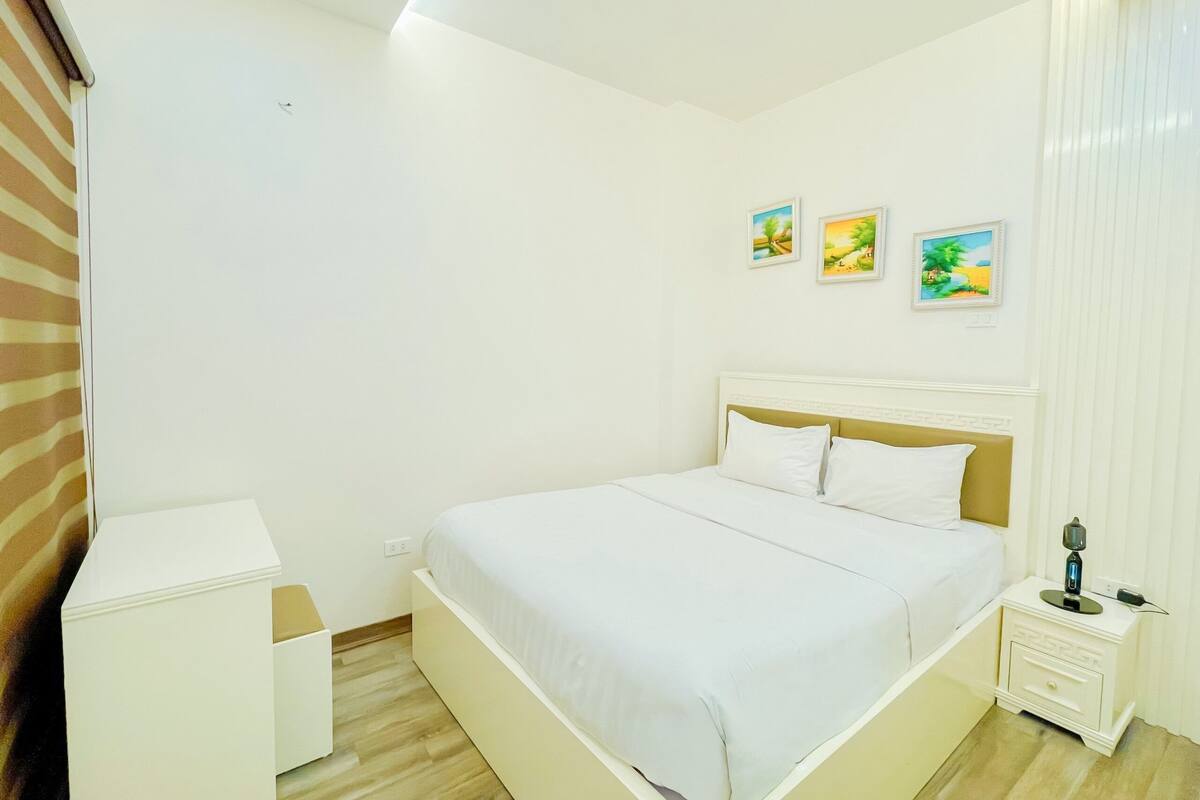 A bedroom with a bed, bedside tables, and wall art.