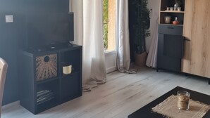 Una sala de estar con un mueble multimedia negro, una mesa de centro negra y una ventana con cortinas ligeras.