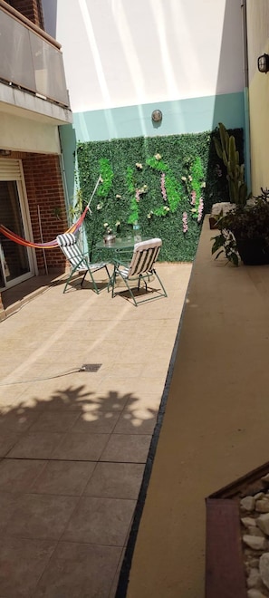 Une terrasse extérieure agrémentée d’un mur végétal, d’un cactus et d’un hamac.