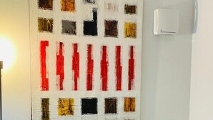 Un espace repas moderne avec une table ronde, des chaises blanches et un tableau abstrait aux couleurs vives accroché au mur.