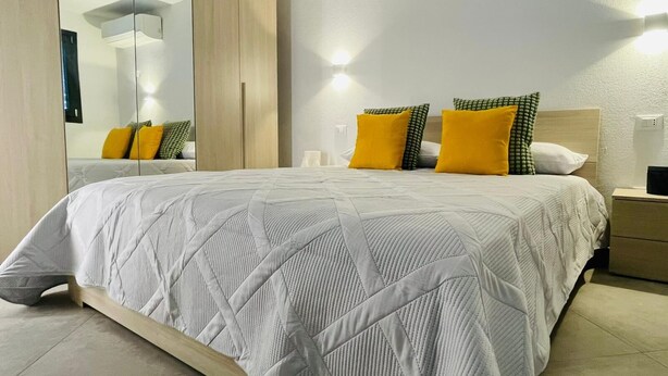 Une chambre à coucher moderne avec un grand lit, une armoire et une table de chevet.