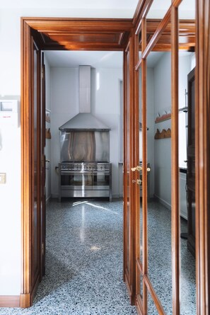 Une cuisine équipée d’une cuisinière en acier inoxydable, d’une hotte aspirante et de meubles de rangement en bois.