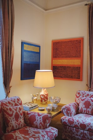 Ein Wohnzimmer mit gemusterten Sesseln, einem Tisch mit Dekoration und zwei Wandbildern.
