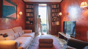 A living room with a sofa, a patterned ottoman, a television, and a bookshelf. - Villa Dell Artista by Elite Villas (Cernobbio)