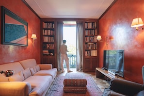 A living room with a sofa, a patterned ottoman, a television, and a bookshelf. - Villa Dell Artista by Elite Villas (Cernobbio)