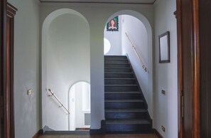 Un escalier muni d’une rampe, bordé de murs blancs et de portes en bois.