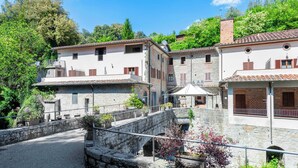 A traditional stone building with a stone bridge, surrounded by greenery and trees. - Exclusive Resort & Waterfall - A14 (Loro Ciuffenna)