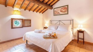 A well-lit bedroom with a wooden ceiling, a bed with white linens, a tray with breakfast items, and two bedside lamps. - Exclusive Resort & Waterfall - A14 (Loro Ciuffenna)