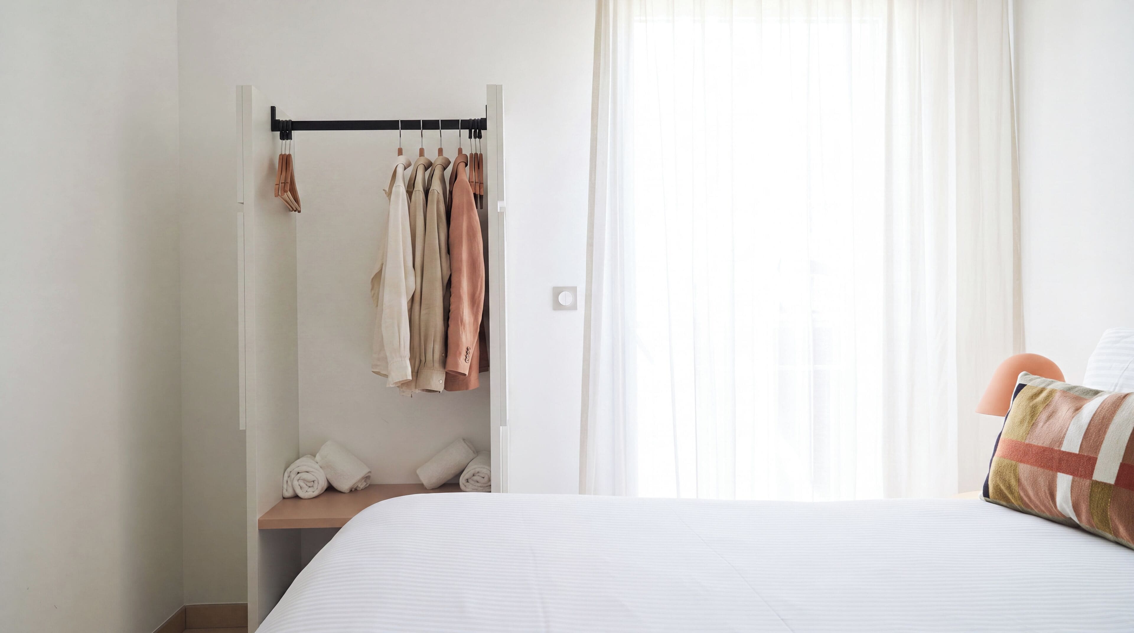 Ein Schlafzimmer mit einem Bett, einem Einbauschrank und einem Fenster mit Vorhängen.