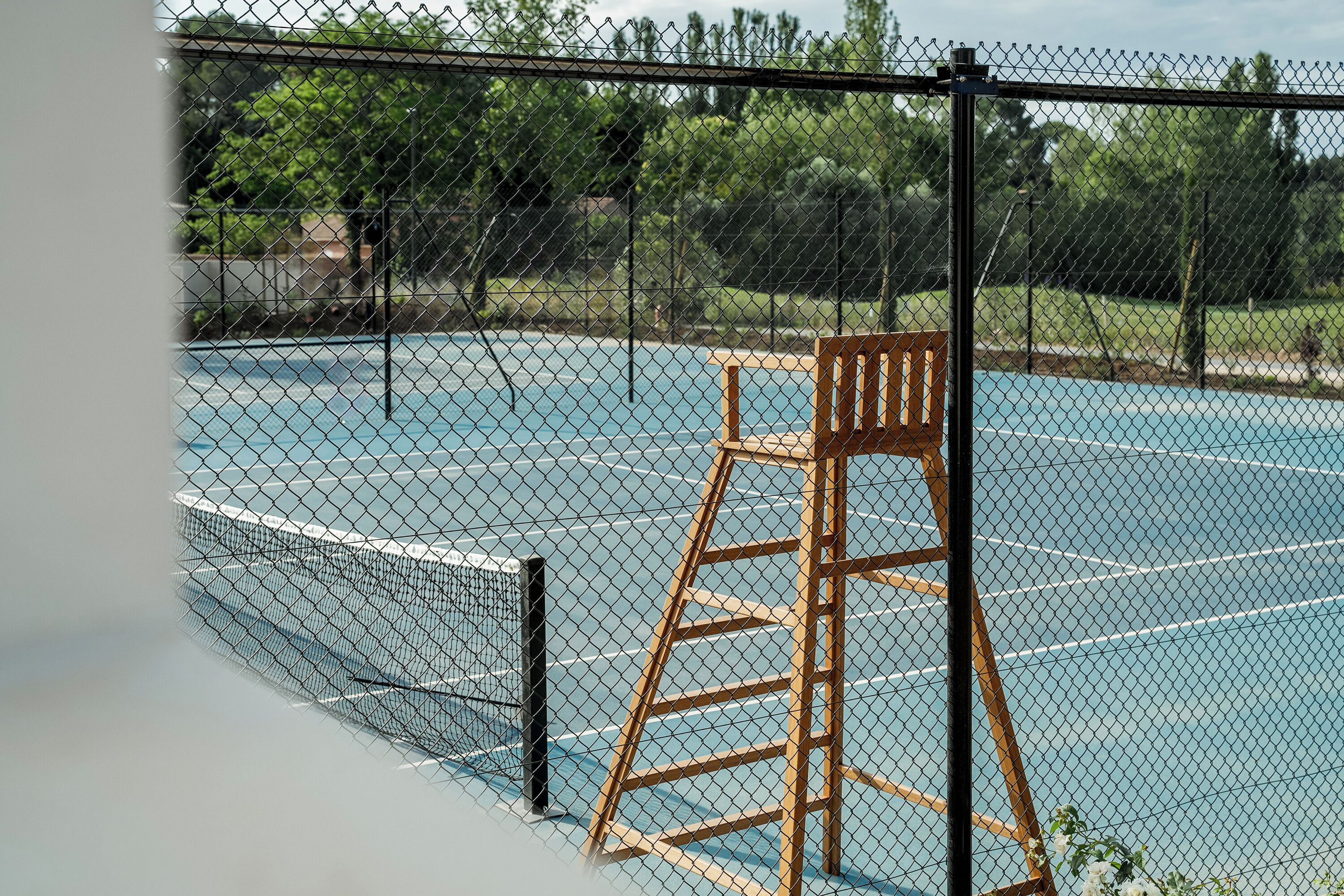 A tennis court with a wooden chair and a net.