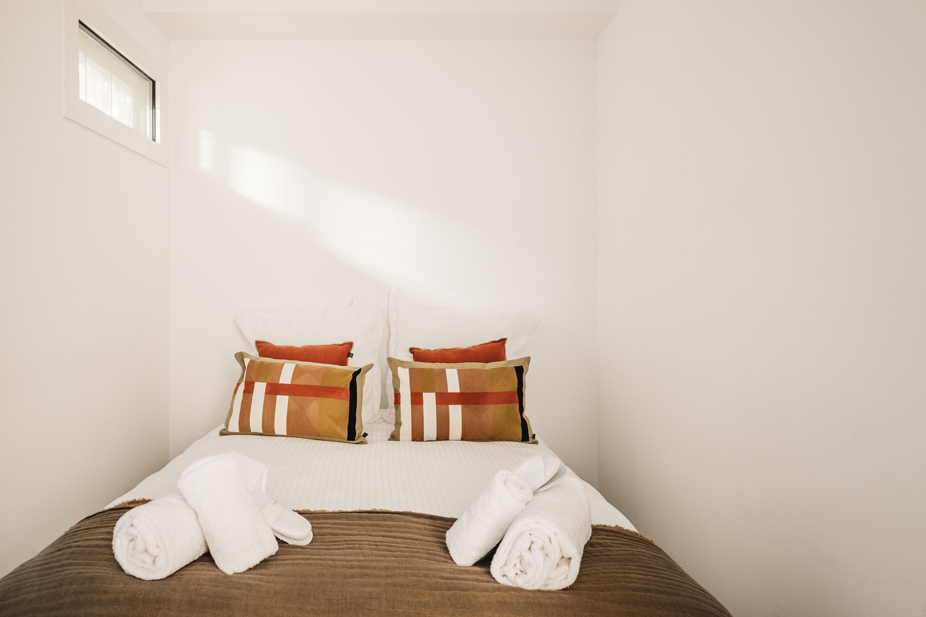 Quarto de hotel com cama, almofadas e toalhas.