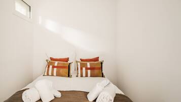 Quarto de hotel com cama, almofadas e toalhas.