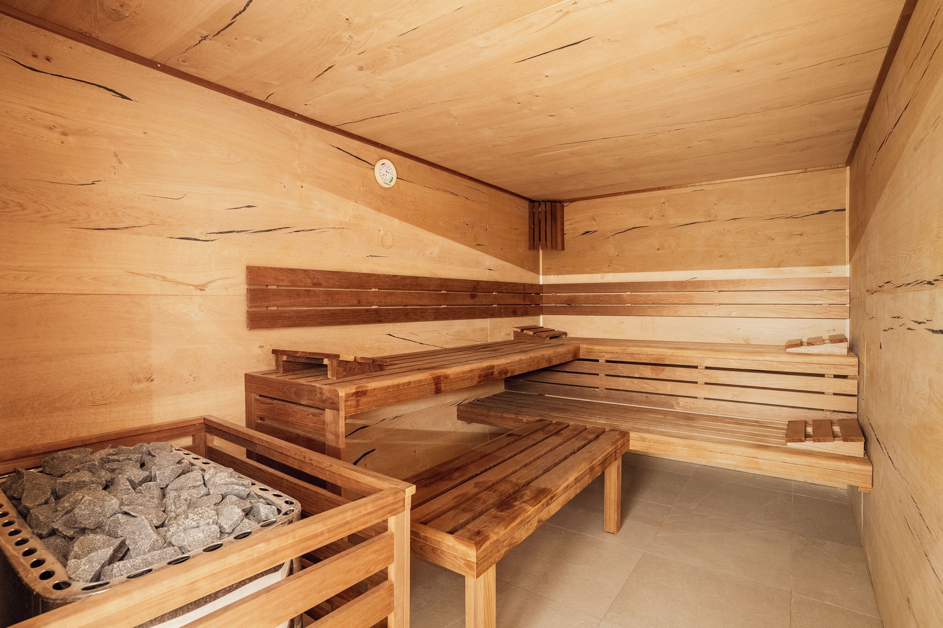 Un cuarto de sauna con bancos de madera y un calentador de piedra.