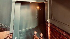 Una escalera con barandilla de madera y una lámpara sobre la puerta.