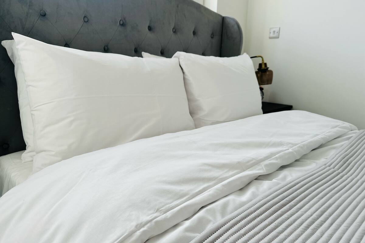 A neatly made bed with white bedding and a tufted headboard.