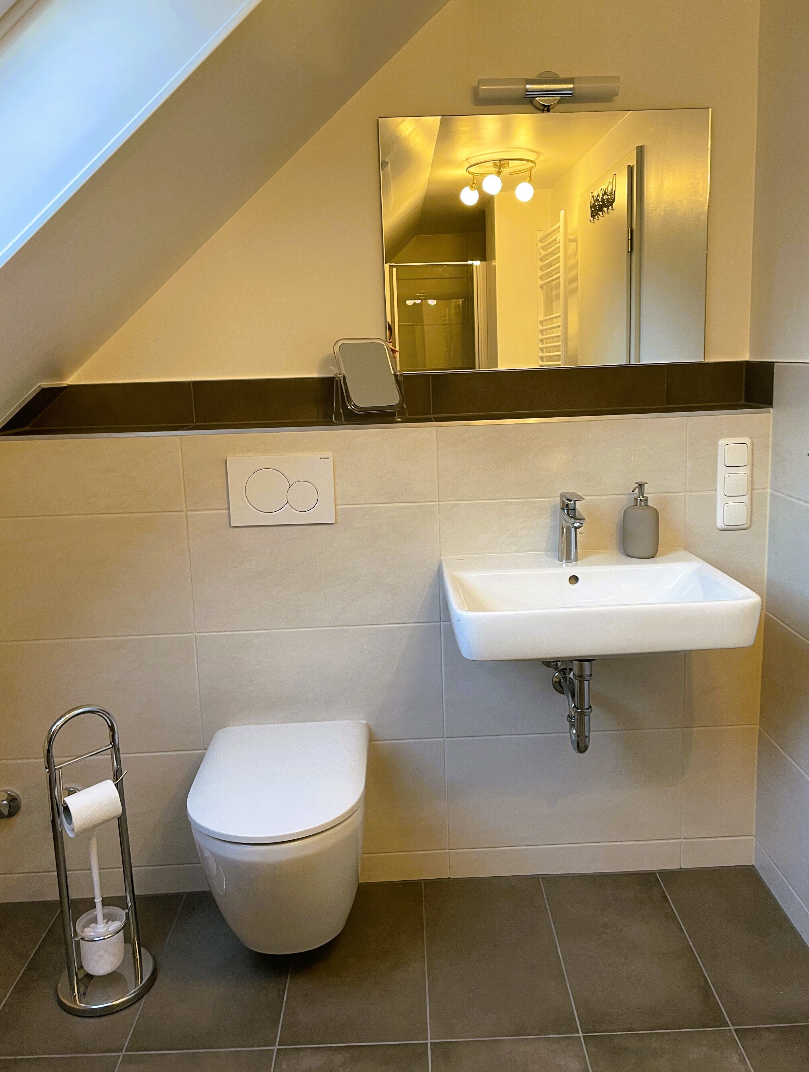 Un baño moderno con un inodoro blanco, un lavabo y un espejo.