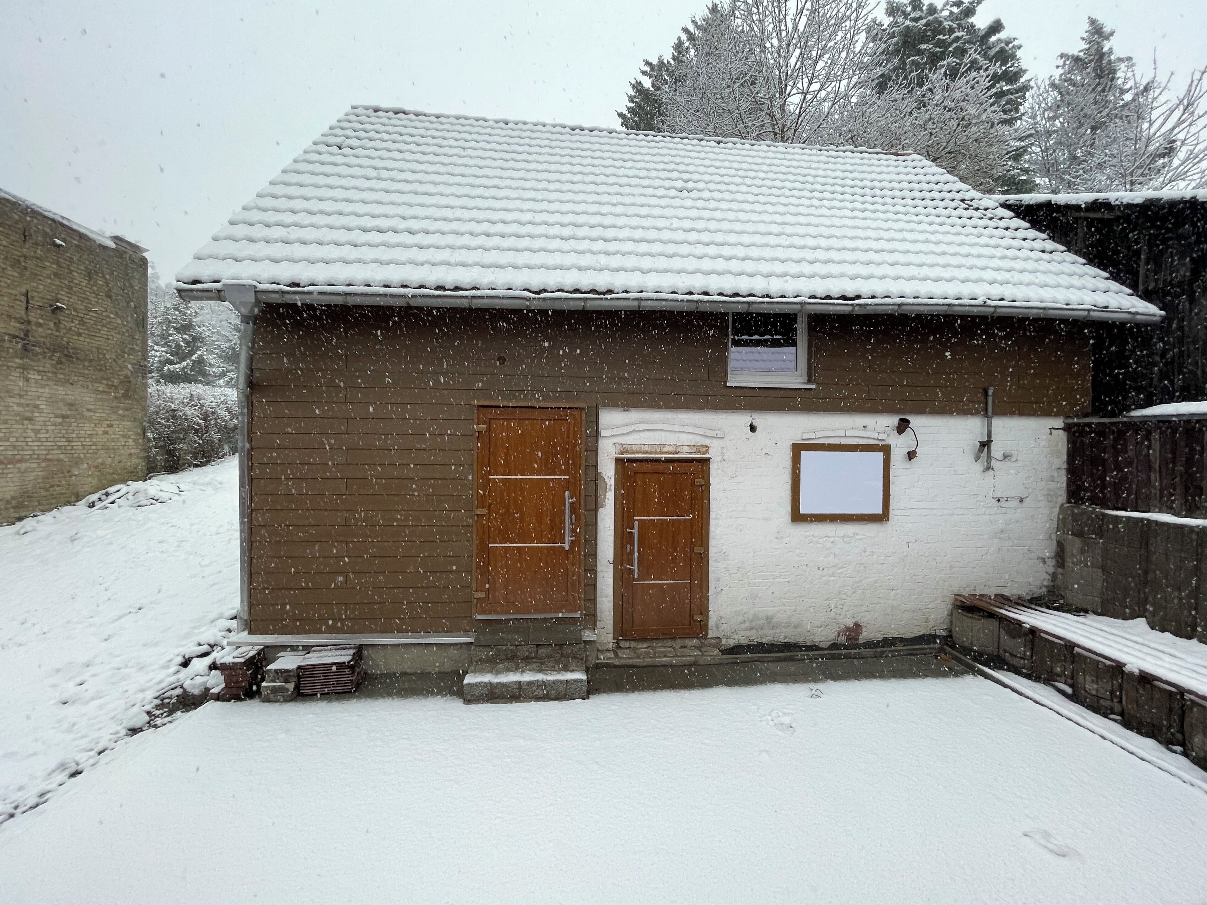 A small, single-story building with a snow-covered roof and a brick exterior.