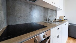 A modern kitchen with a built-in stove, a sink, and white cabinets. - Azores Element - House with pool (Ponta Delgada)