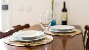 A dining table with plates, a wine bottle, and a glass. - Azores Element - House with pool (Ponta Delgada)