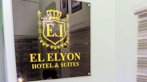 Un letrero de vidrio con el logotipo y el nombre de El Elyon Hotel & Suites.