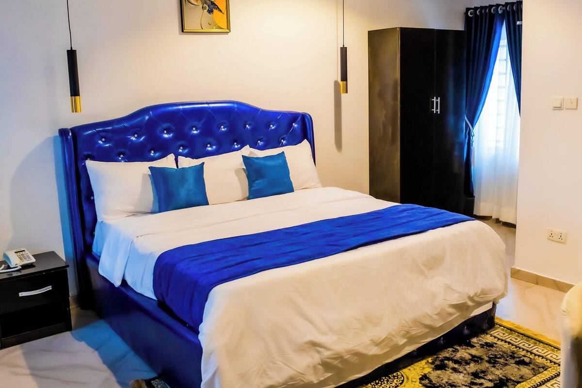 Un dormitorio moderno con una cama grande, un armario negro y una lámpara en el techo.