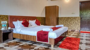 A neatly made bed with a red headboard, a wooden wardrobe, and a red rug on a patterned floor.
