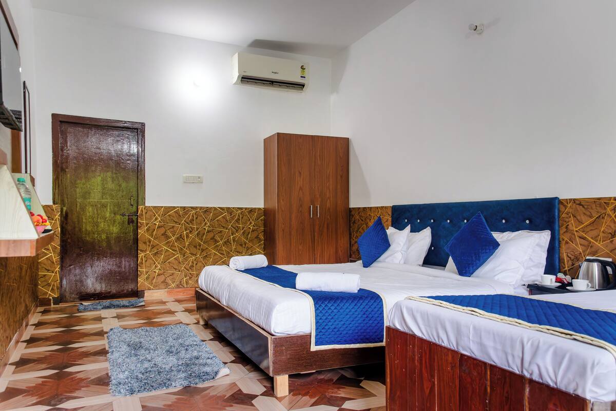 A hotel room with two beds, a wardrobe, a door, and a patterned floor.