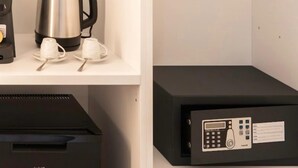 A coffee maker, two white cups, and a black electronic device on a white shelf. - Metropolitan Rooms (Cagliari)