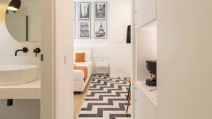 A modern bathroom with a white sink, a round mirror, and a black floor lamp. - Metropolitan Rooms (Cagliari)