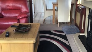 A cozy RV interior with a red leather couch, a wooden table with a remote control, and a checkered floor. - Beautiful 2-bed Chalet in Llanfairpwllgwyngyll (Llanfairpwllgwyngyll)