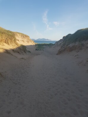 A sandy beach with dunes and a dog in the distance. - Beautiful 2-bed Chalet in Llanfairpwllgwyngyll (Llanfairpwllgwyngyll)