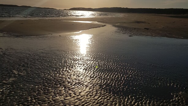 A beach with the sun low on the horizon, reflecting on the wet sand. - Beautiful 2-bed Chalet in Llanfairpwllgwyngyll (Llanfairpwllgwyngyll)